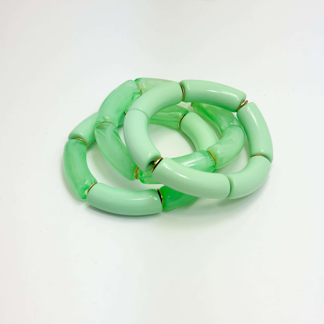 A set of mint green acrylic bracelets displayed on a white background.