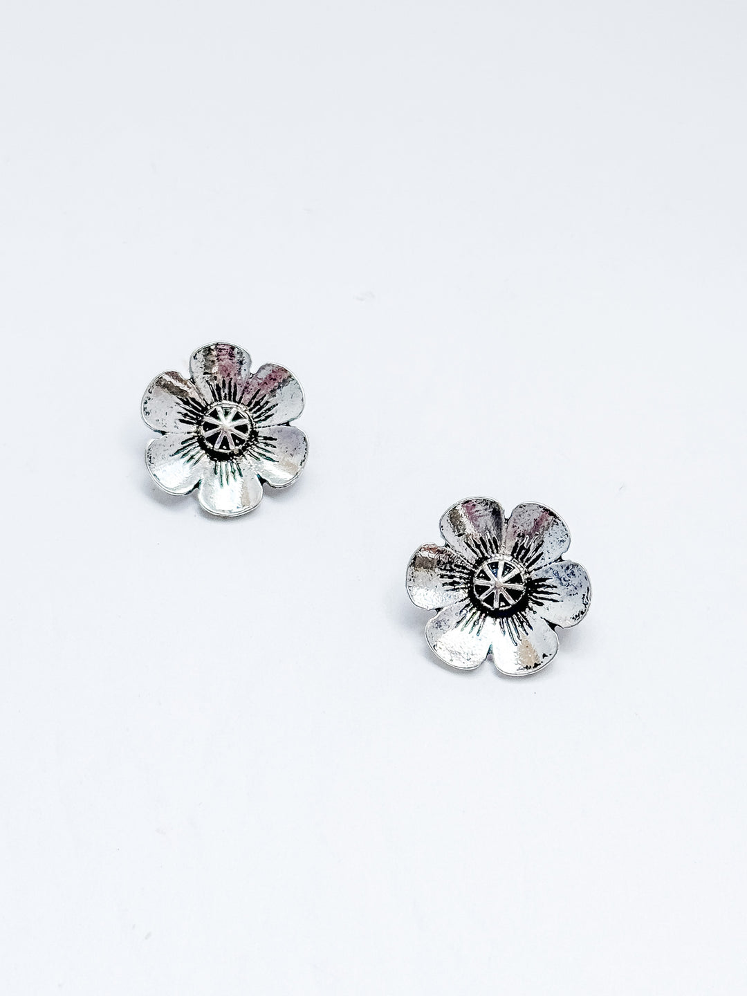 Flower-shaped silver earrings on a white background