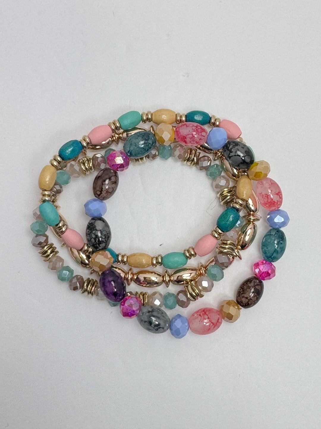 A set of multicolored beaded bracelets with gold accents, featuring a variety of geometric shaped beads and gold bead caps.