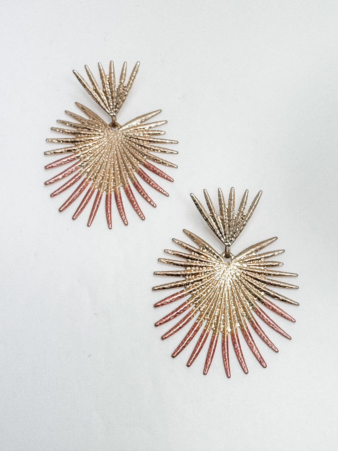 two gold sunburst earrings with blush pink accents