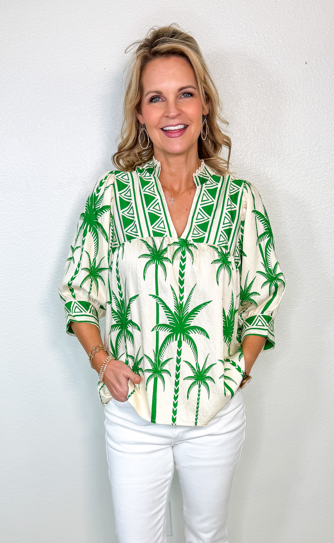 Woman wearing a green palm tree patterned blouse against a white background