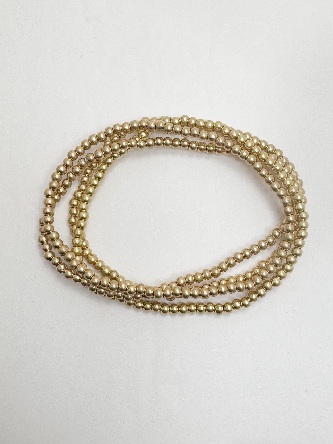 set of petite gold beaded bracelets