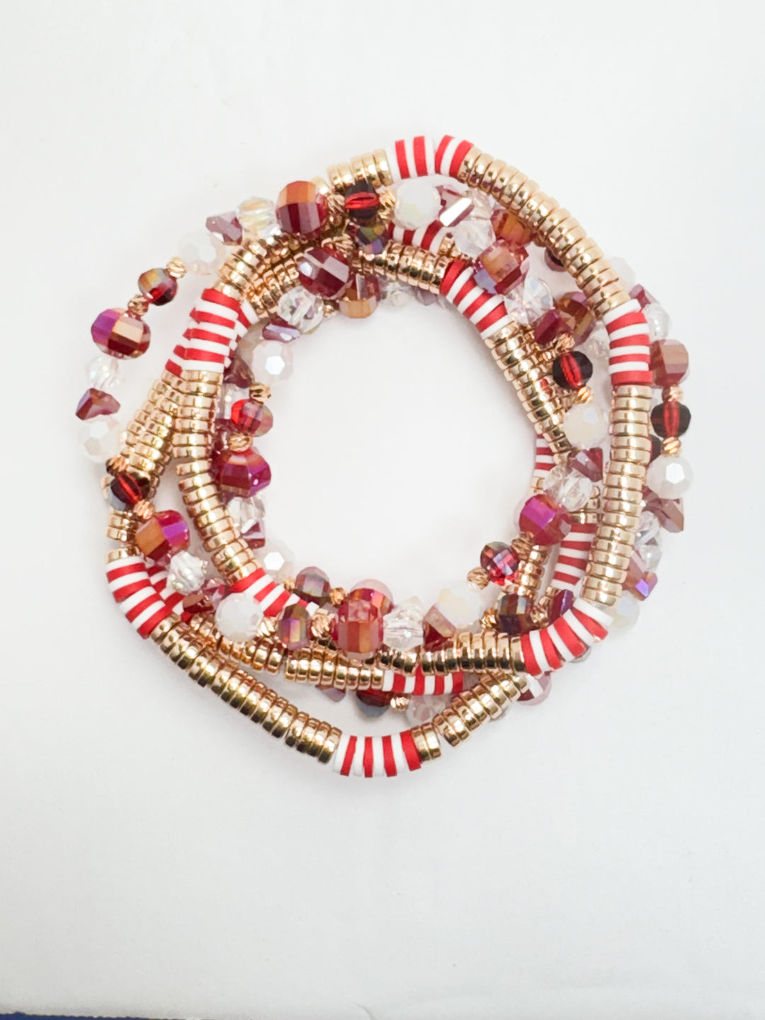 A set of stackable beaded bracelets featuring a variety of colors including red, gold, and white, with textured and smooth beads.
