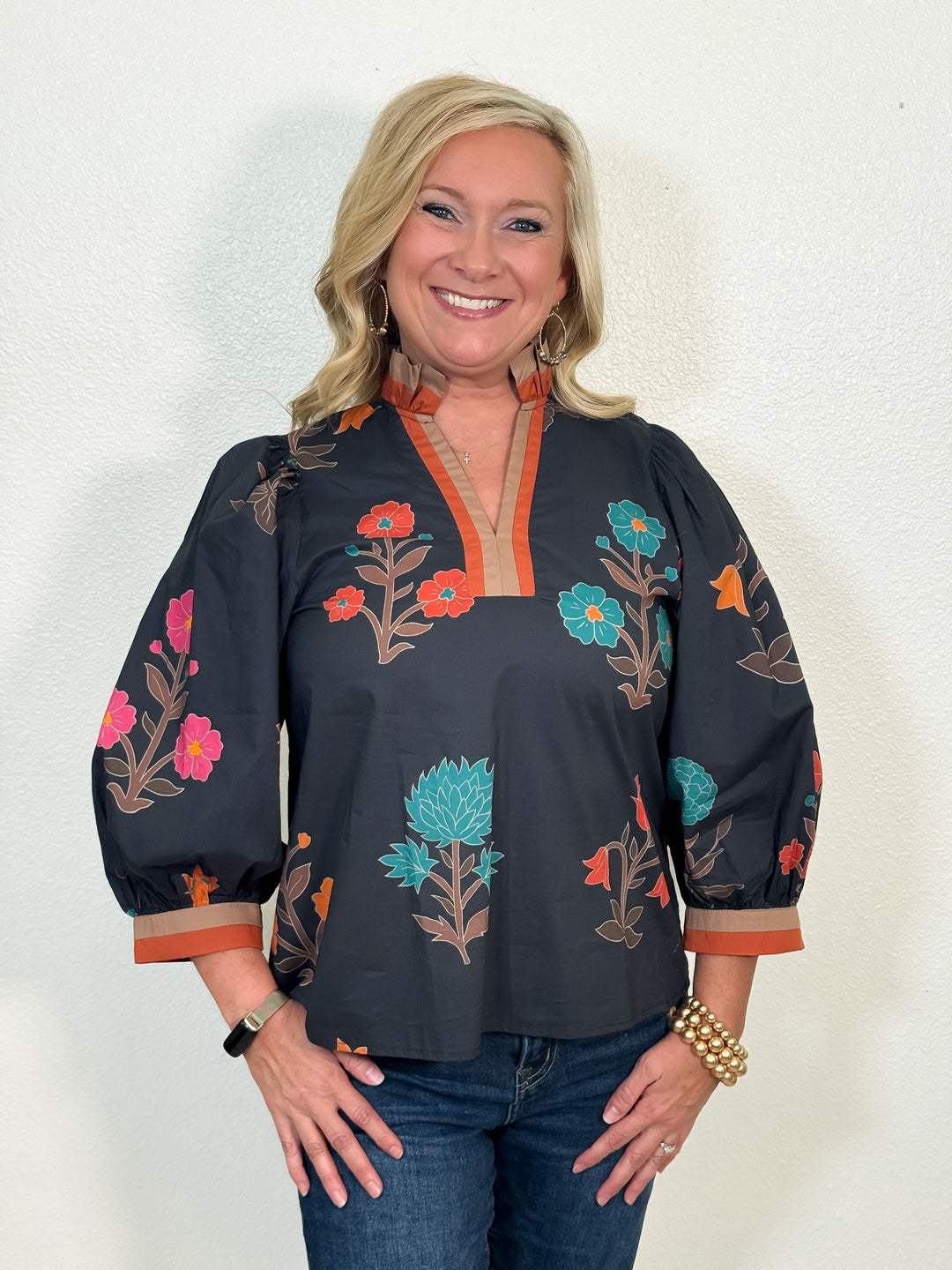 Woman wearing a black blouse with floral embroidery against a white background