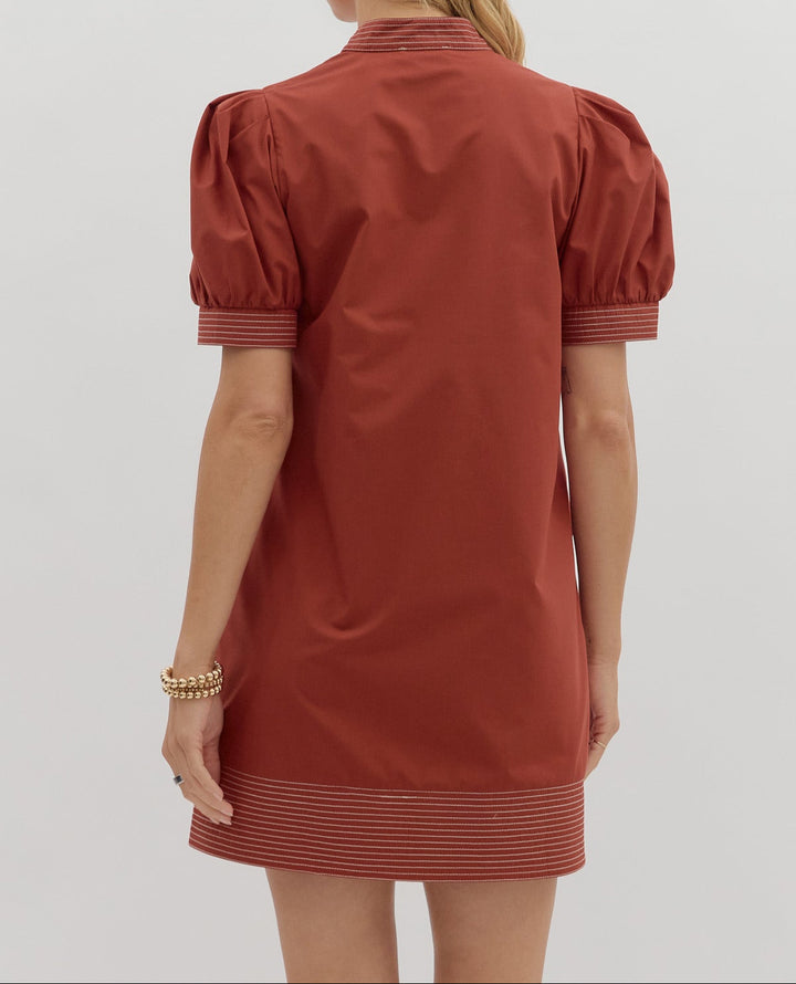 Woman wearing a rust-colored dress with puff sleeves on a white background