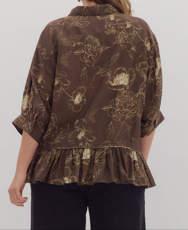 Woman wearing a brown floral blouse with a ruffled bottom on a white background