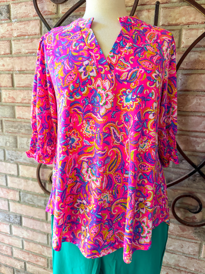 Colorful floral patterned top on a mannequin against a brick wall.