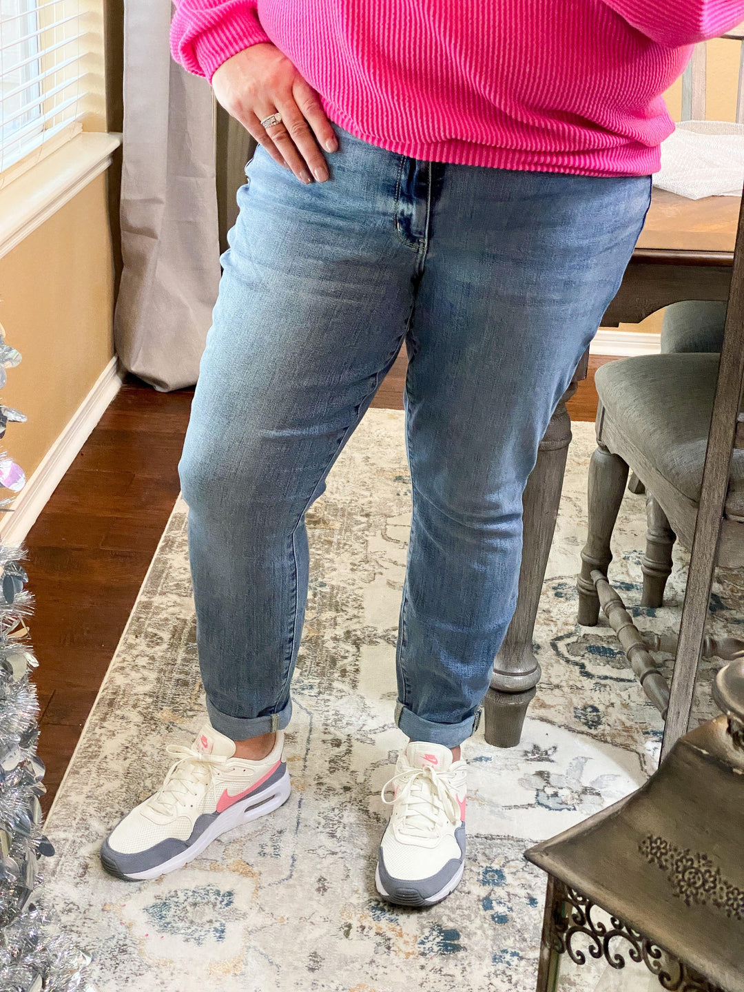 model wearing lightwash jeans pink top and tennis shoes