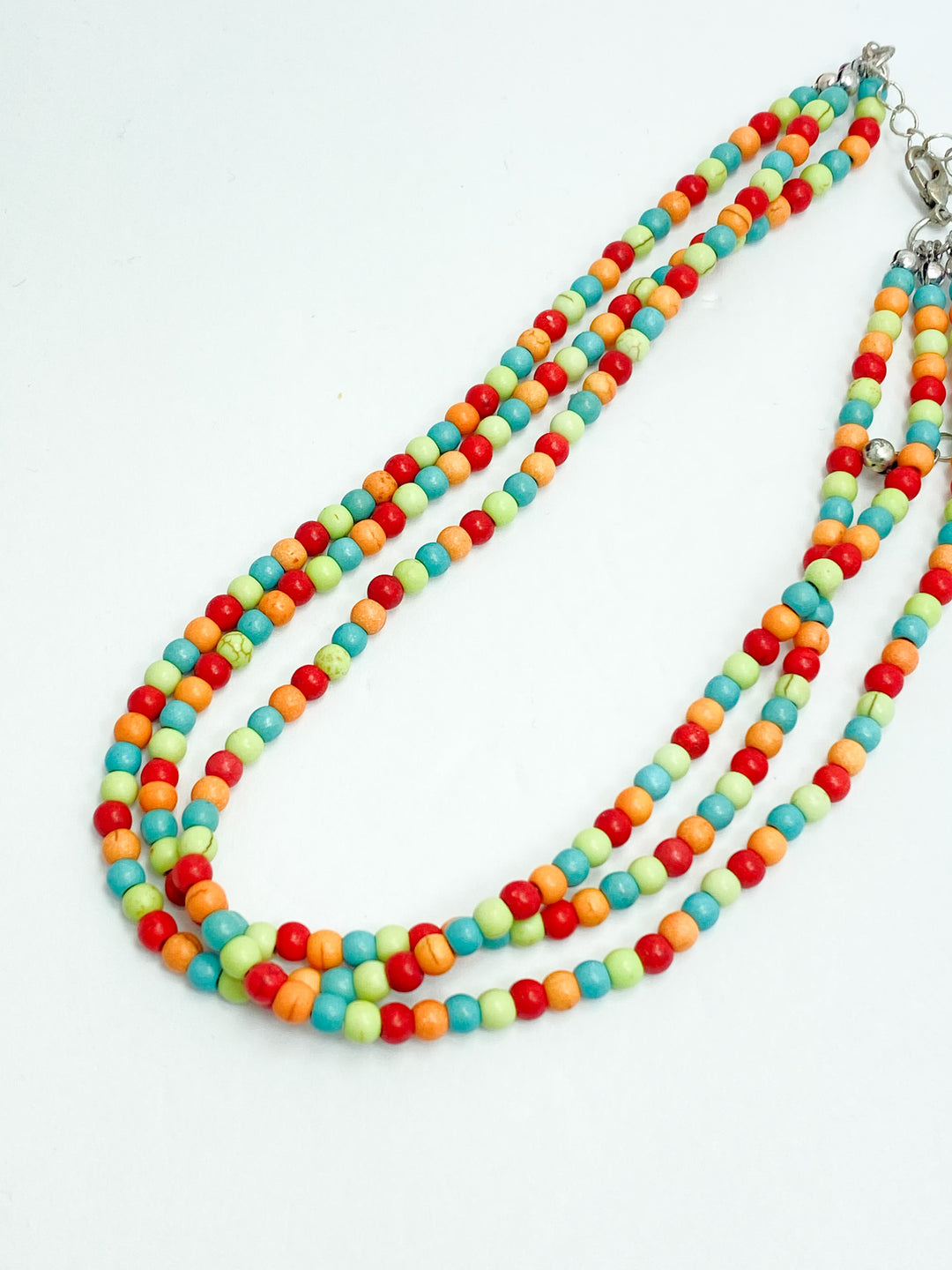 A multicolored beaded choker necklace with orange, turquoise, red, and lime green beads on a white background.