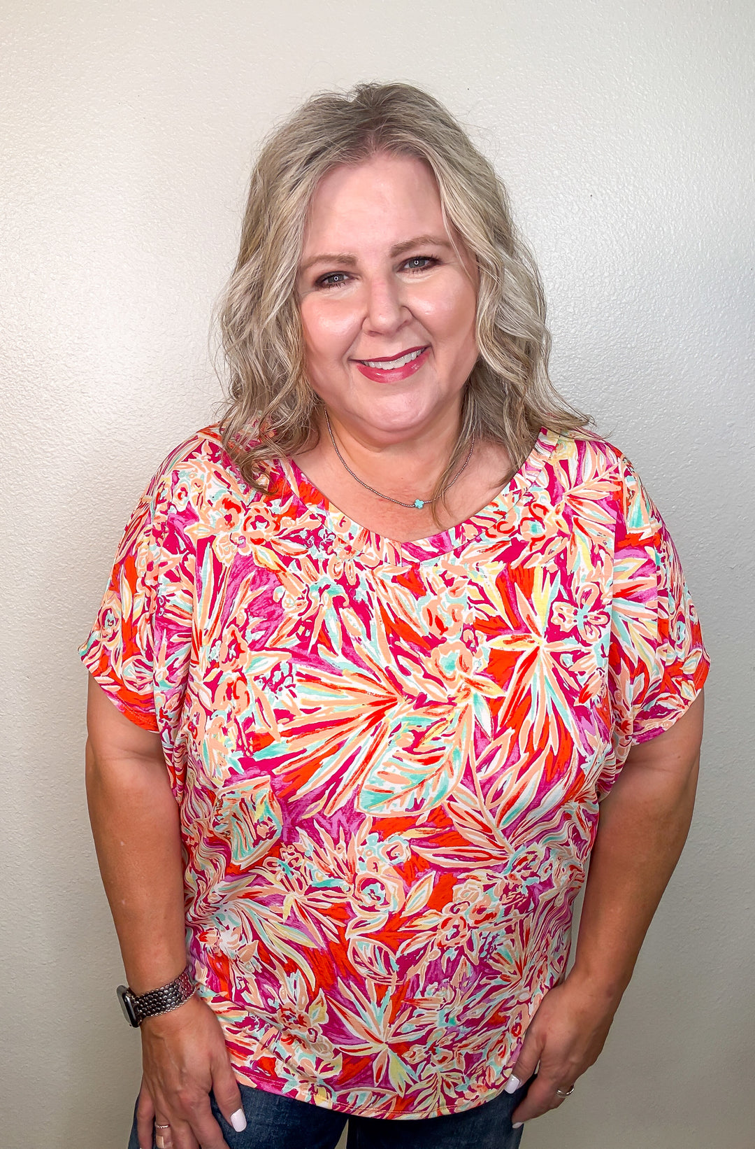 Woman wearing a colorful floral shirt against a plain background