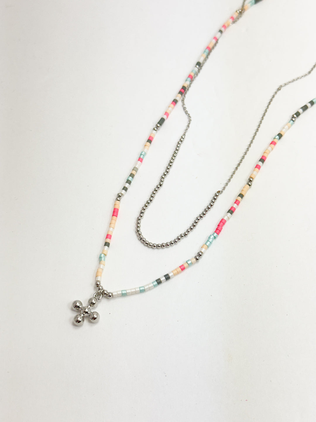 A multicolored beaded layered necklace with a metal cross pendant, displayed against a white background.