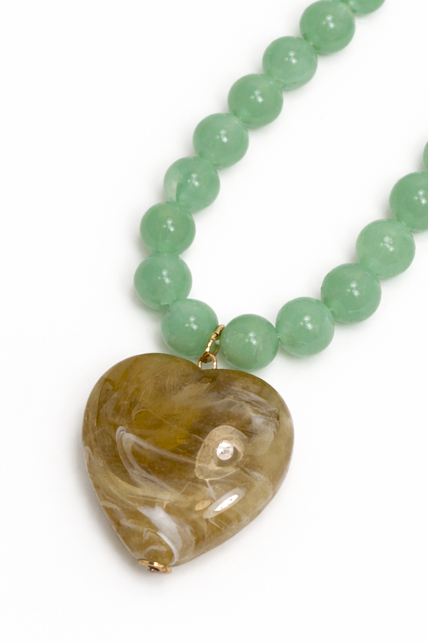 Necklace with green beads and a heart-shaped pendant on a white background