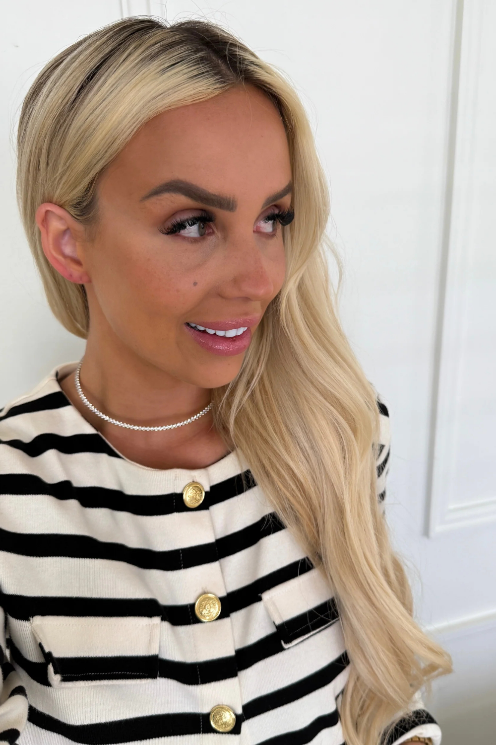 Woman wearing a black and white striped sweater with gold buttons against a white background