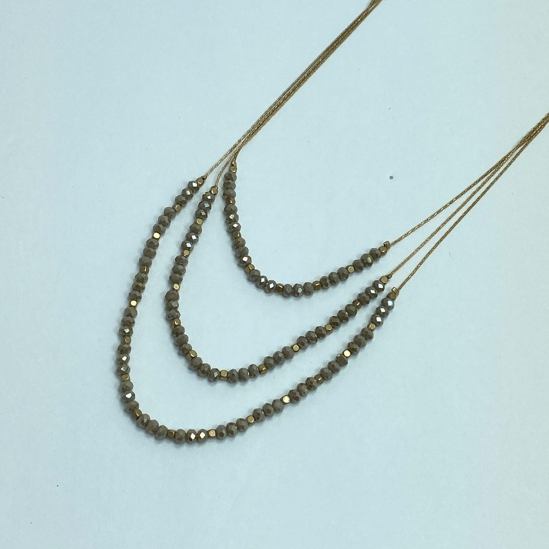 taupe and gold beaded necklace on white background
