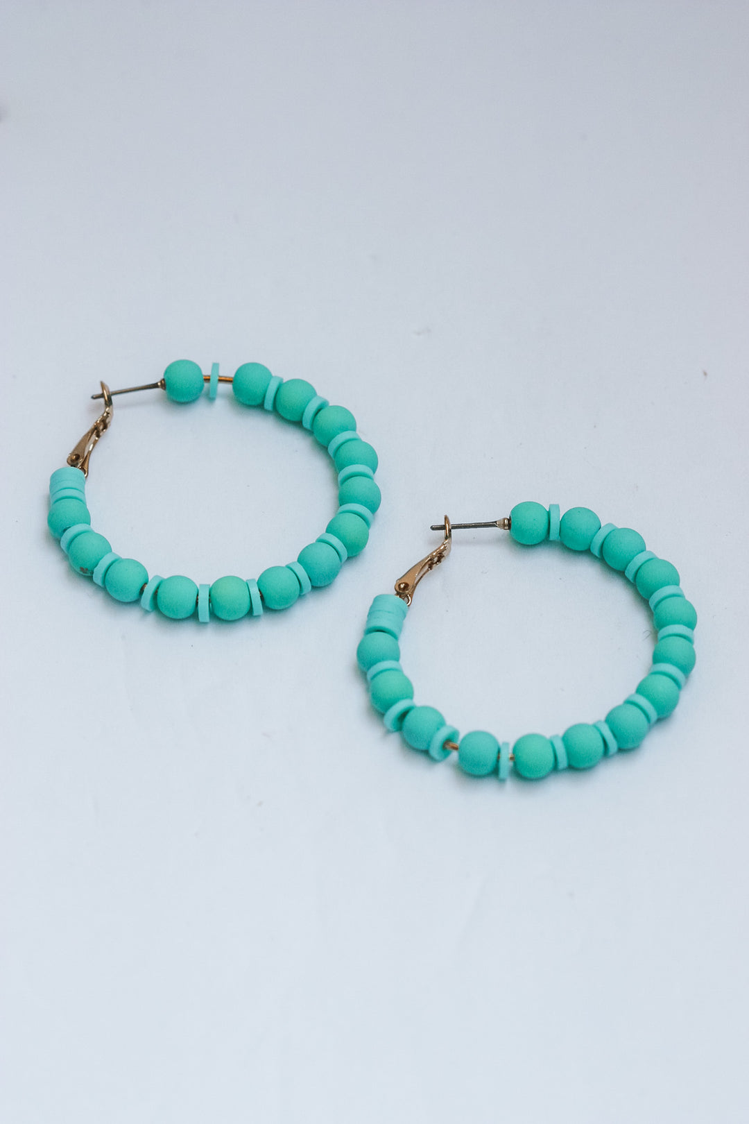 Turquoise beaded hoop earrings on a white background