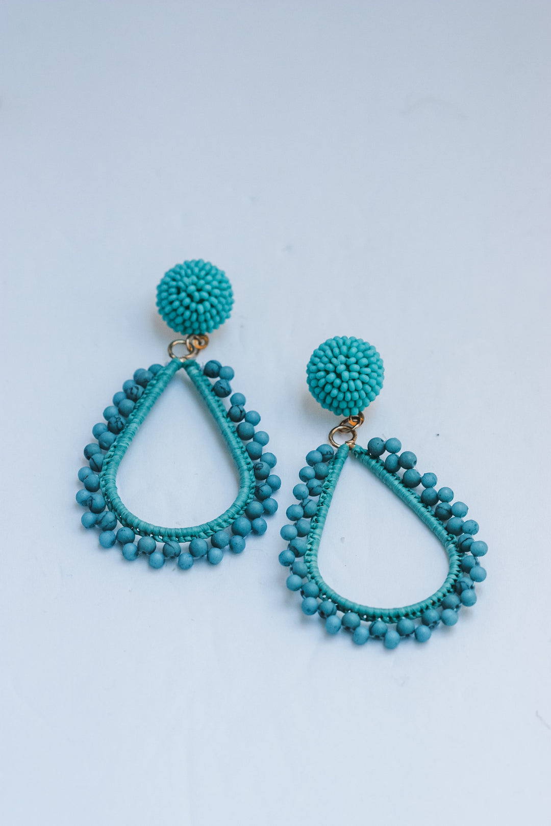 Turquoise beaded earrings on a light blue background