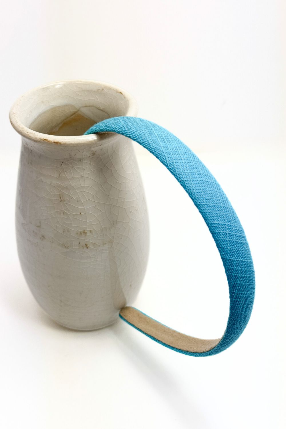 turquoise blue fabric thin headback in a vase on a white background