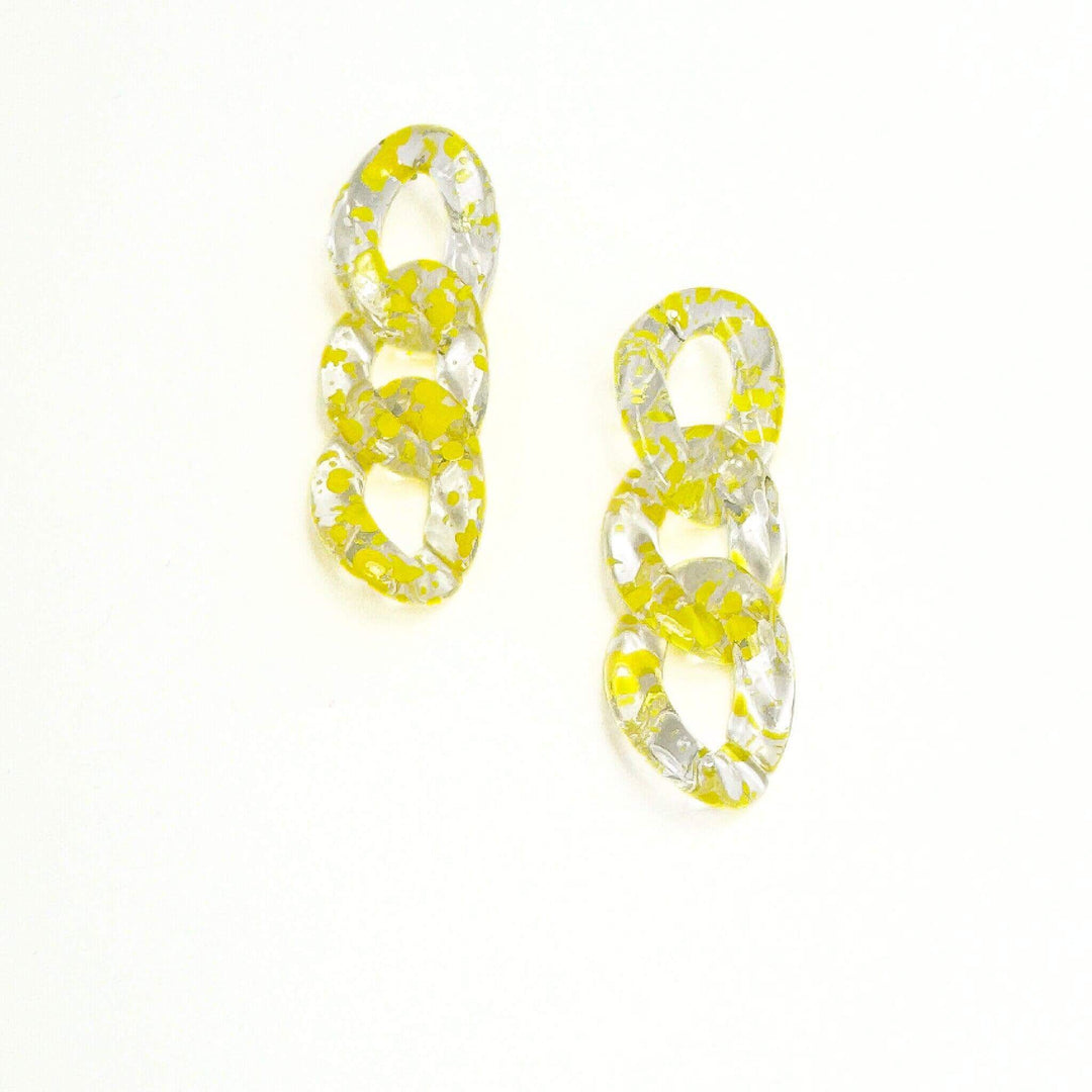 A pair of yellow and clear acrylic link earrings on a white background.