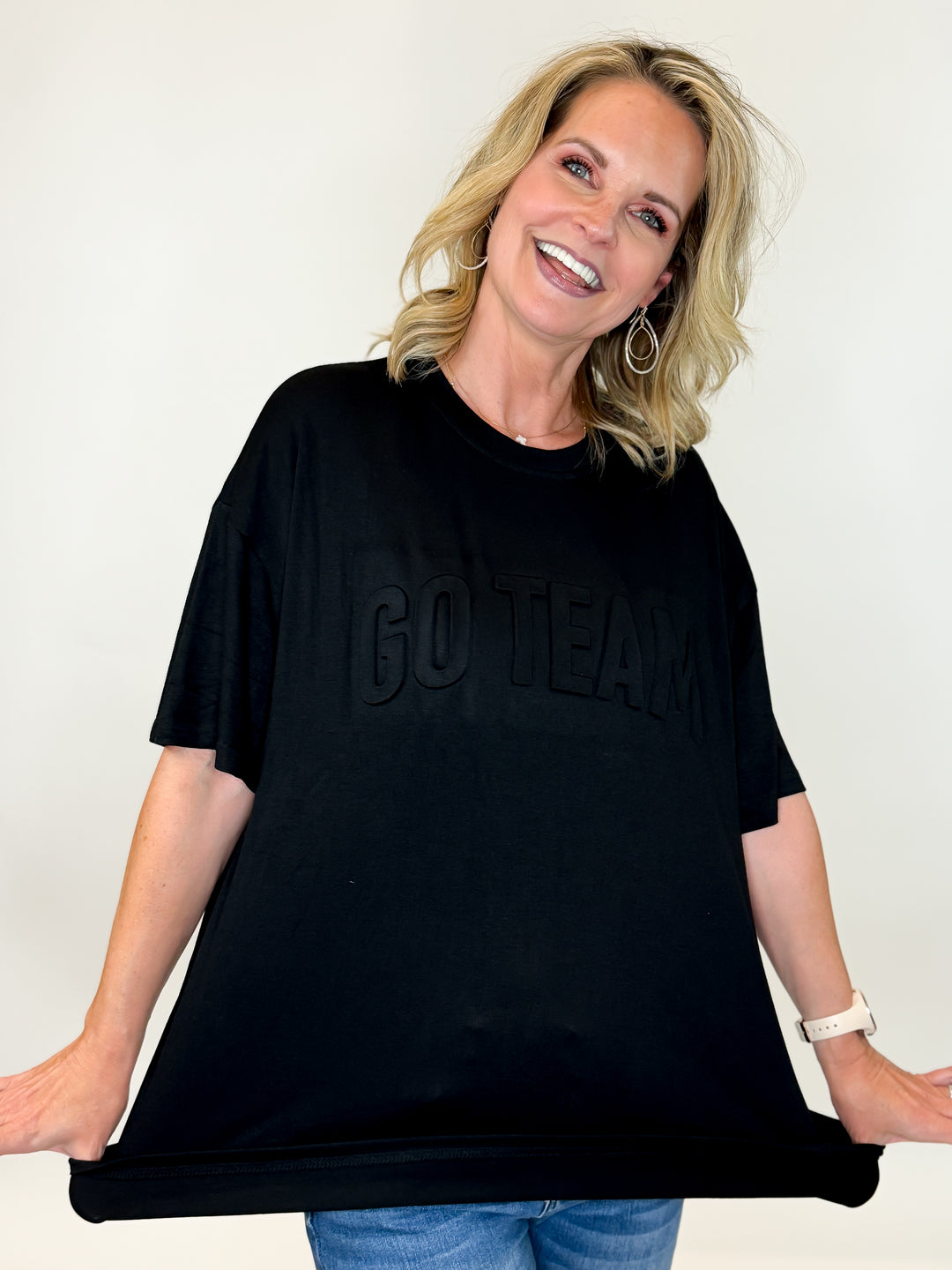 model wearing black tee with GO TEAM lettering across front