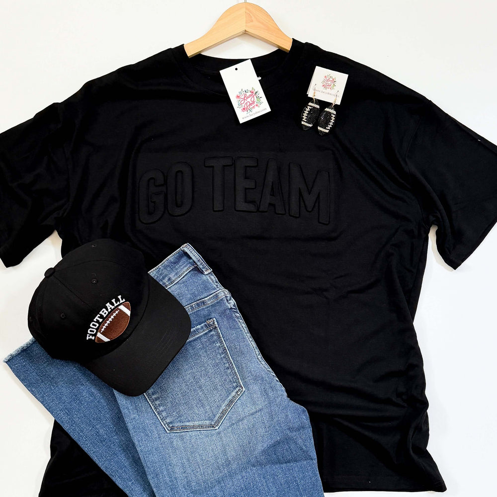 flat lay of black GO TEAM tee with denim jeans black football hat and black rhinestone football earrings