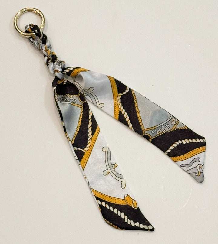 Decorative purse charm with patterned fabric and gold accents on a light background