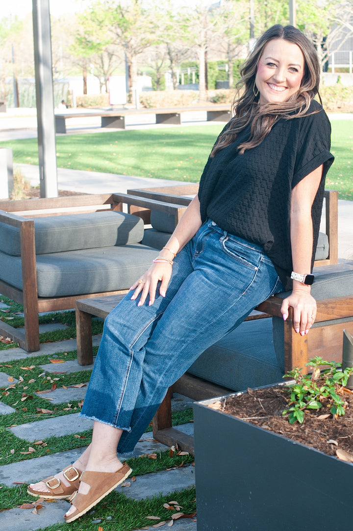model leaning on chair wearing black top