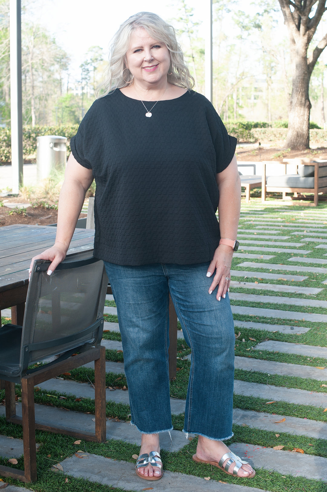 model standing wearing a black textured top and jeans