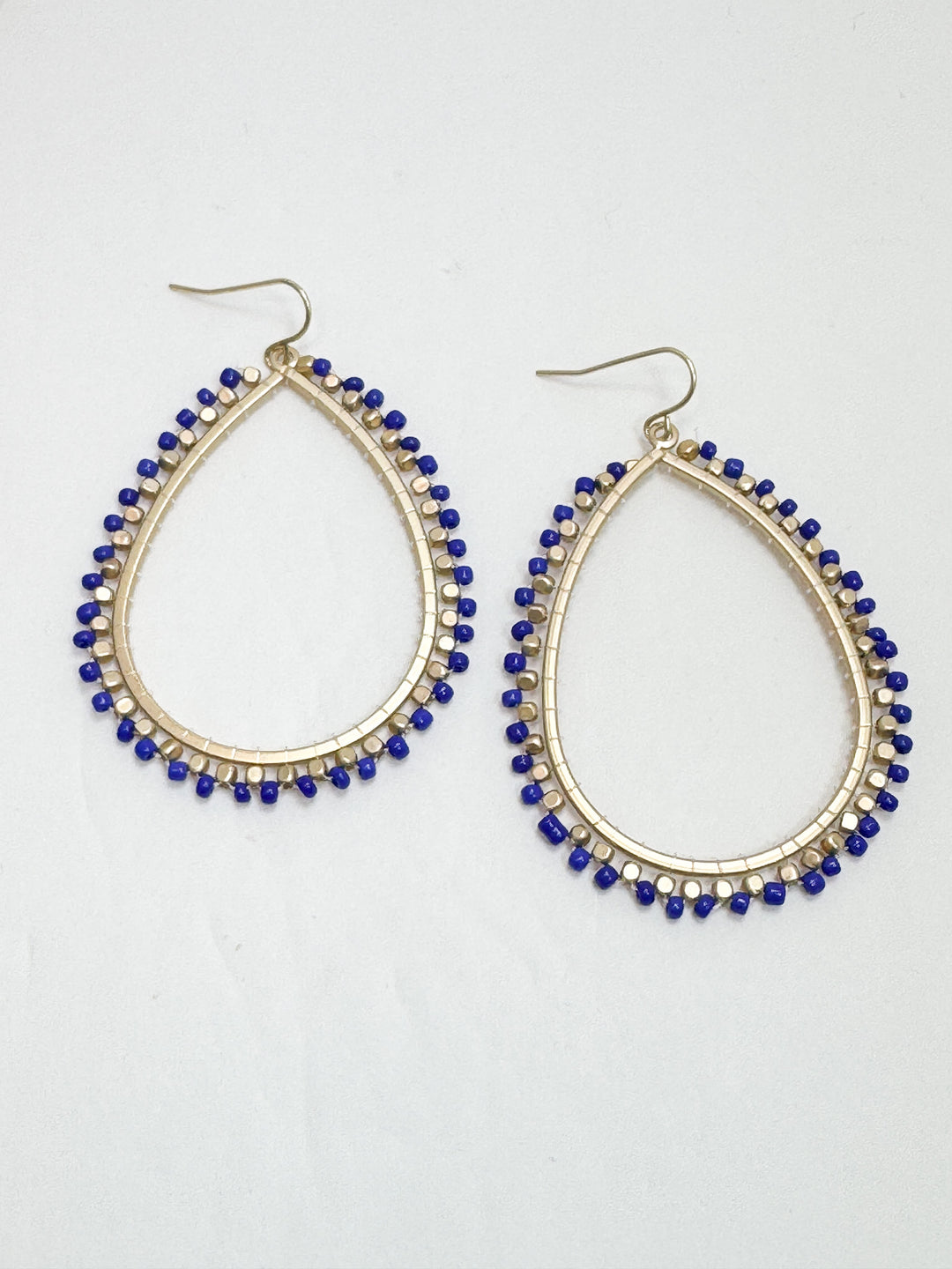 Teardrop-shaped earrings with blue beads on a white background