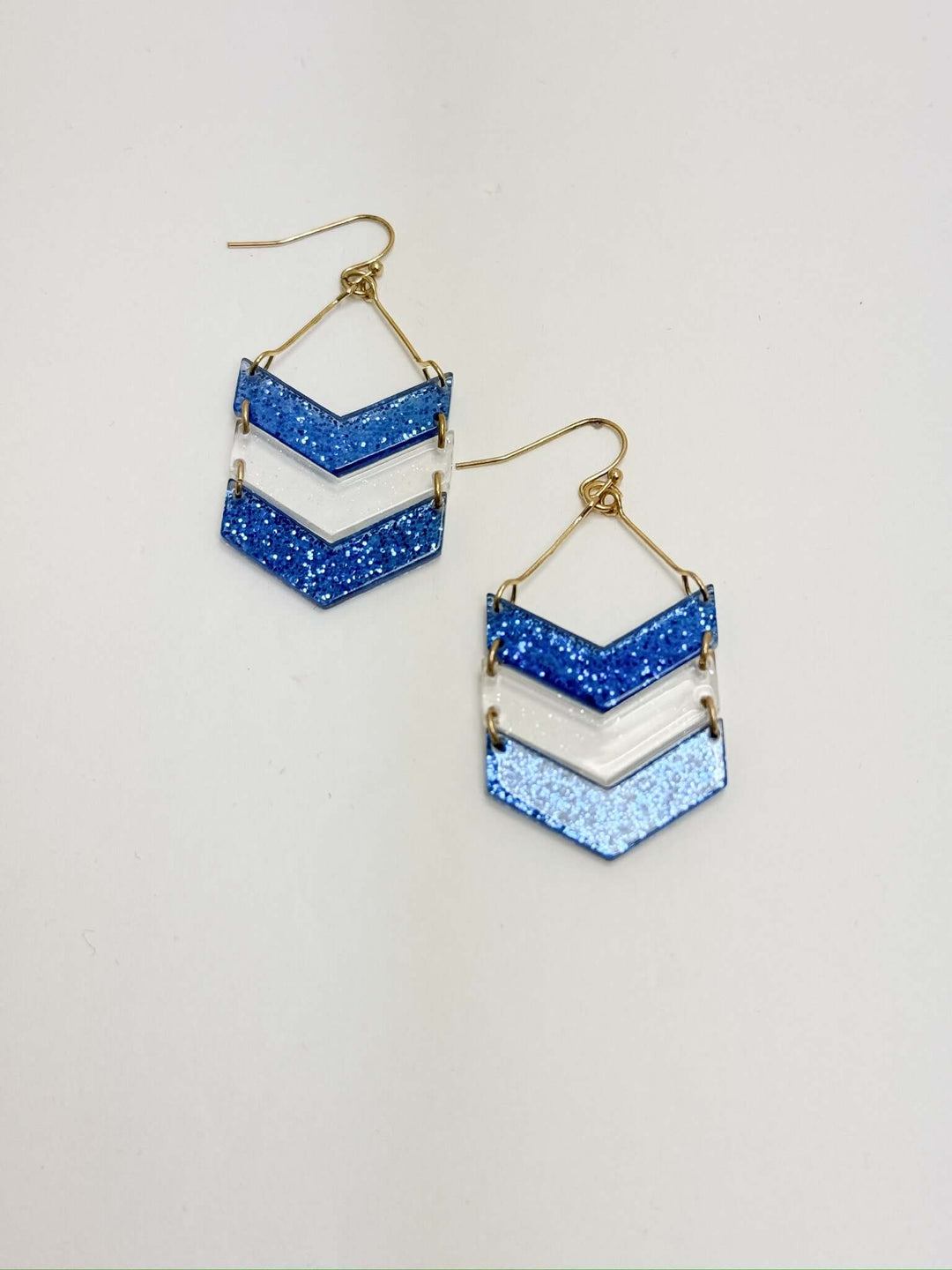 A pair of blue and white chevron earrings with a cascading design, placed on a white surface.