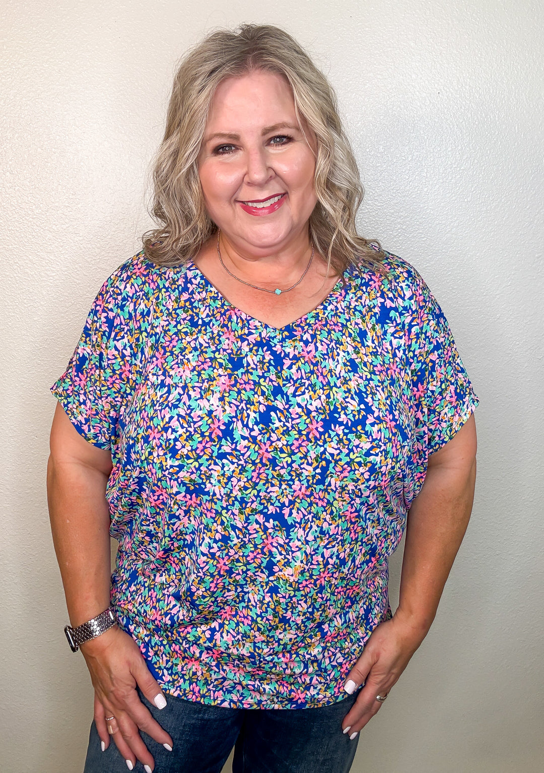 Woman wearing a colorful floral blouse against a plain background