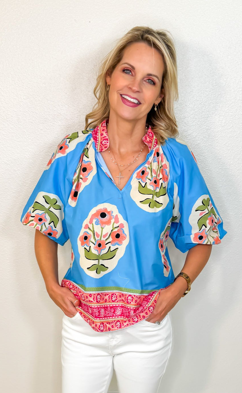 model wearing a vibrant blue coral and pink floral top