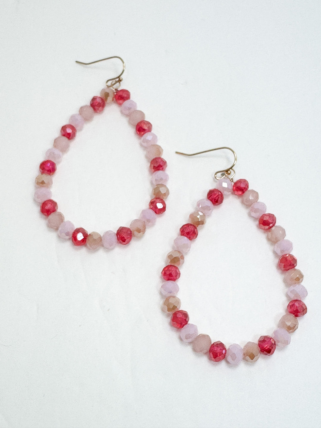 Pair of beaded earrings with pink and red beads on a white background