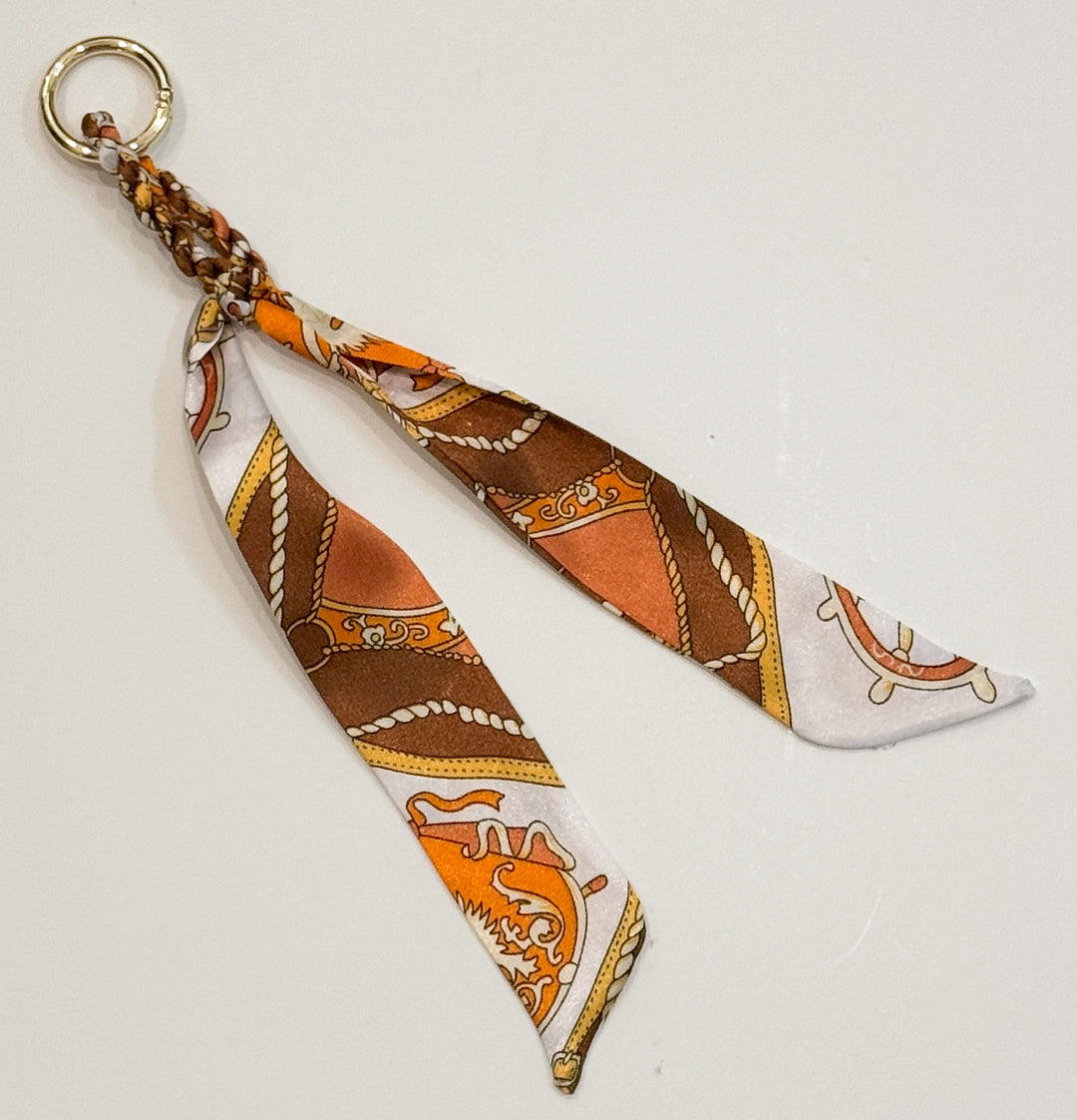 Fabric purse charm with patterned design on a light gray background
