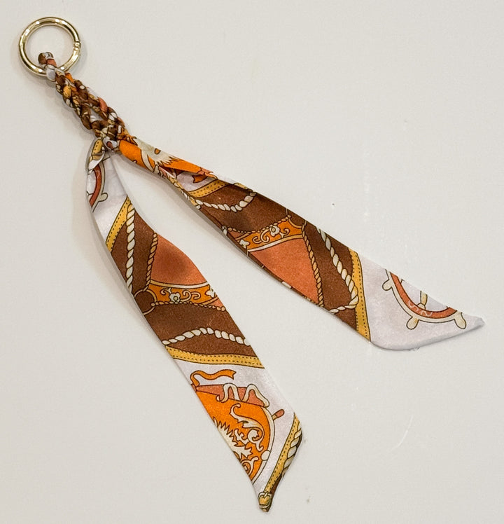 Fabric purse charm with patterned design on a light gray background