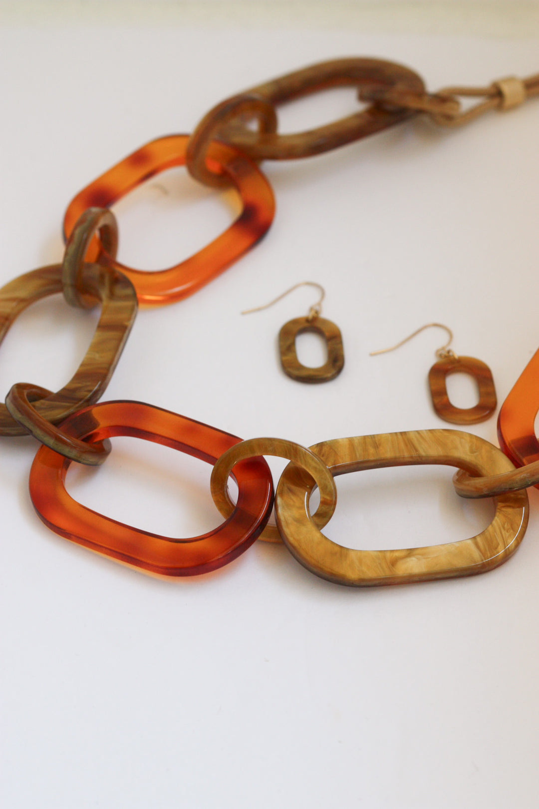 Necklace and earrings with orange and brown links on a white background