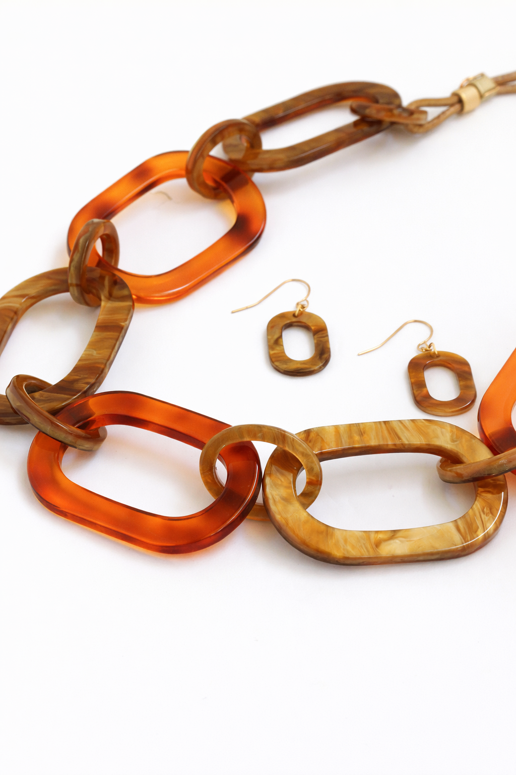 Jewelry set with tortoiseshell chain necklace and earrings on a white background