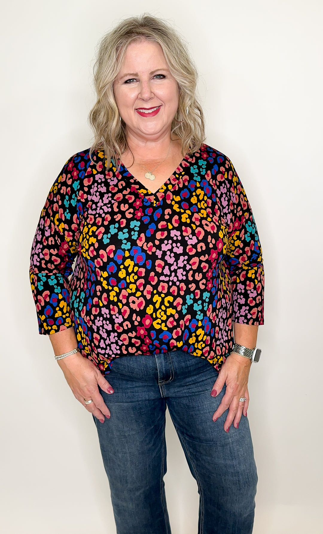 A person wearing a multicolored top with a v-neckline, 3/4 sleeves, and a casual fit.