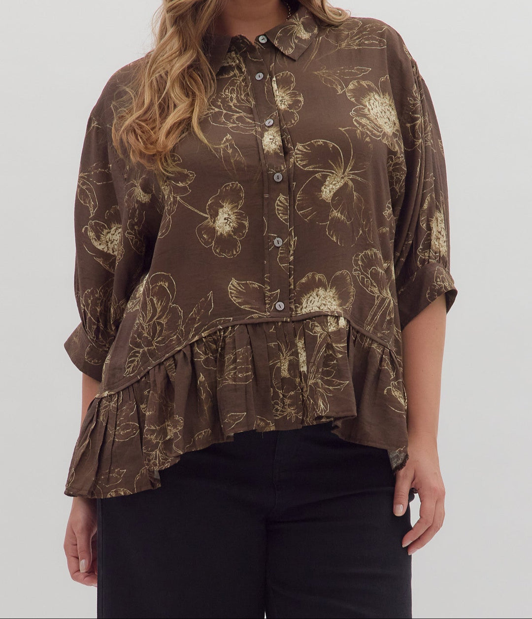 Woman wearing a brown floral blouse against a white background