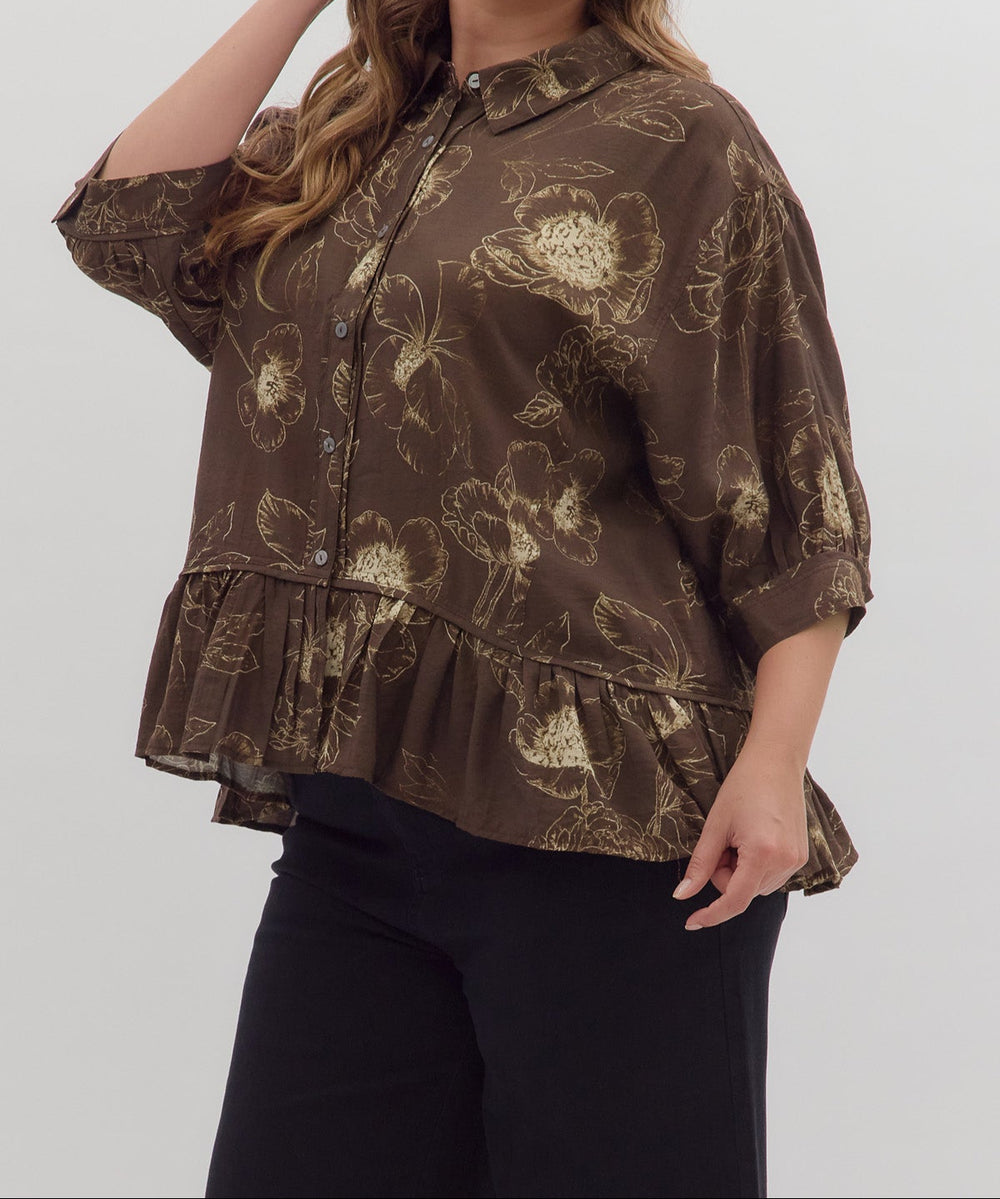 Woman wearing a brown floral blouse against a white background