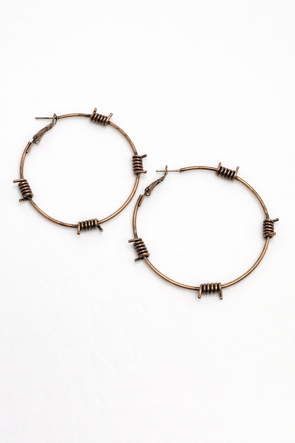 Pair of bronze hoop earrings with barbed wire design on a white background