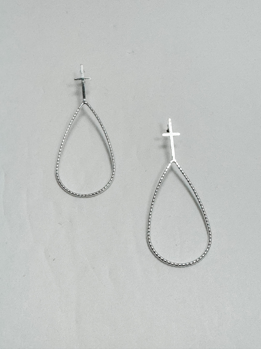 Silver post earrings on a gray background