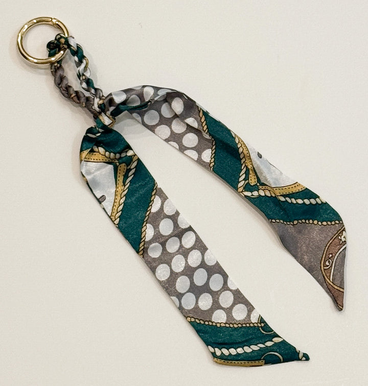 Decorative purse charm with patterned fabric strip on a beige background