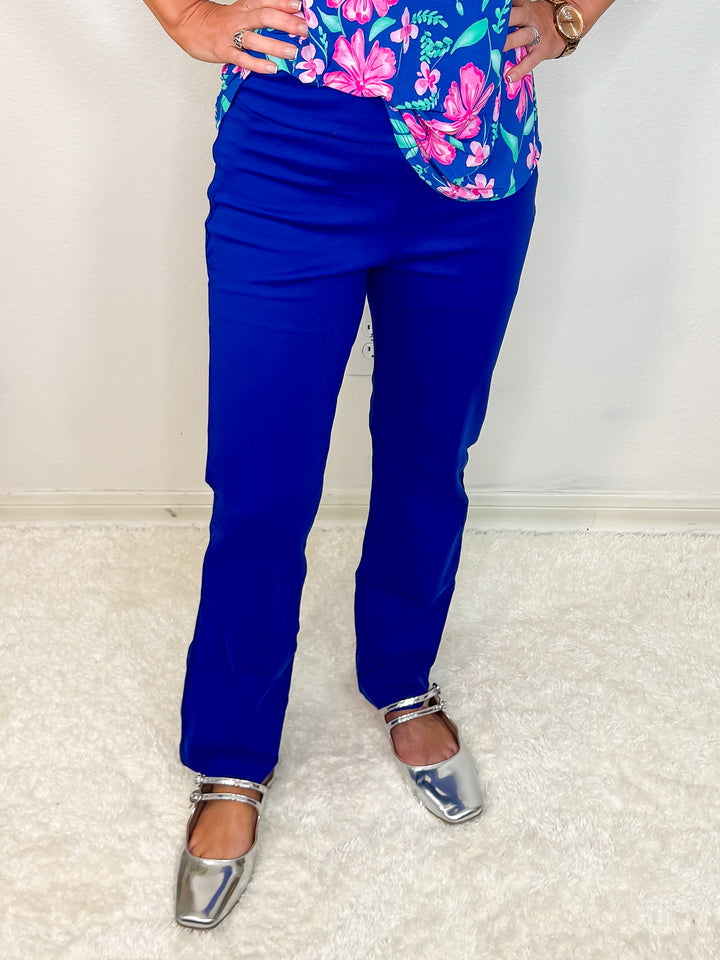 A person wearing a pair of high-waisted, straight-leg blue pants and a multicolored top, with silver shoes.