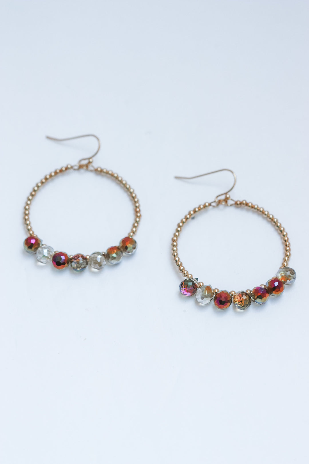 Pair of hoop earrings with colorful beads on a light gray background