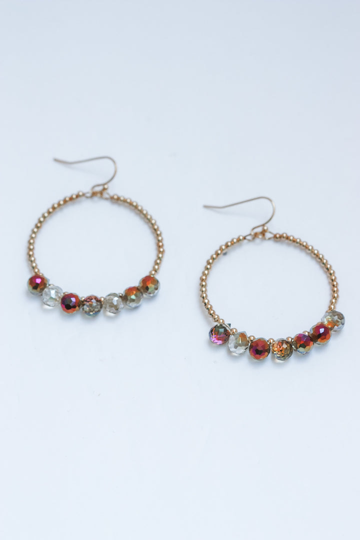 Pair of hoop earrings with colorful beads on a light gray background