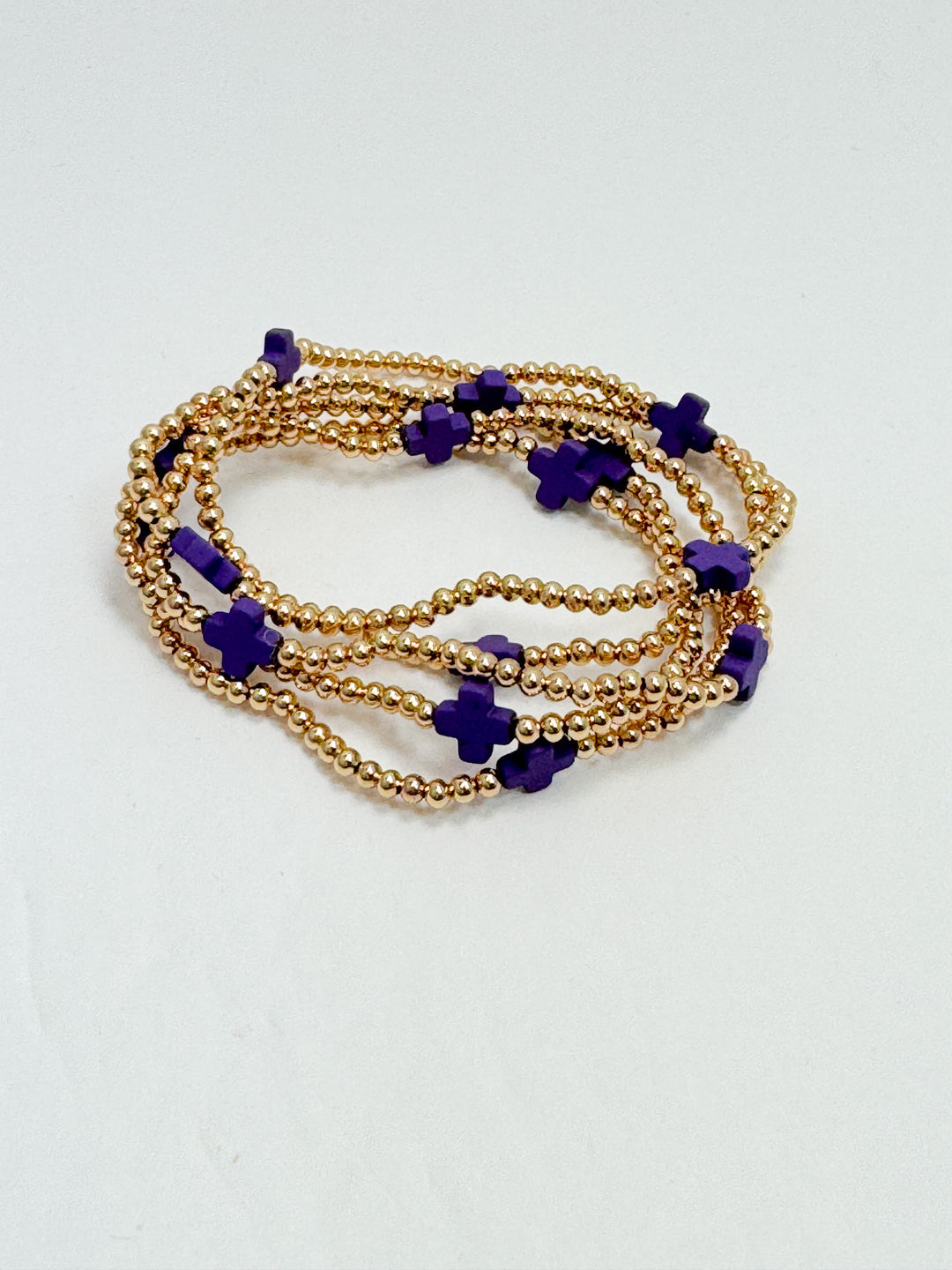 Gold and purple beaded bracelets on a white background