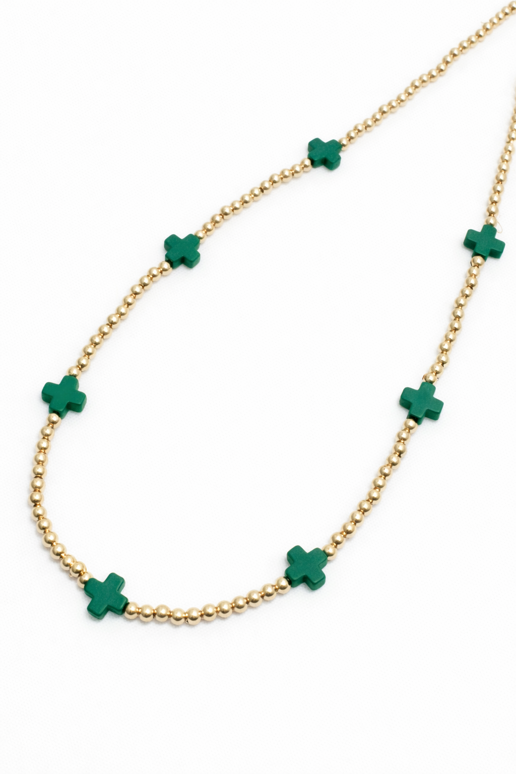Gold necklace with green cross pendants on a white background