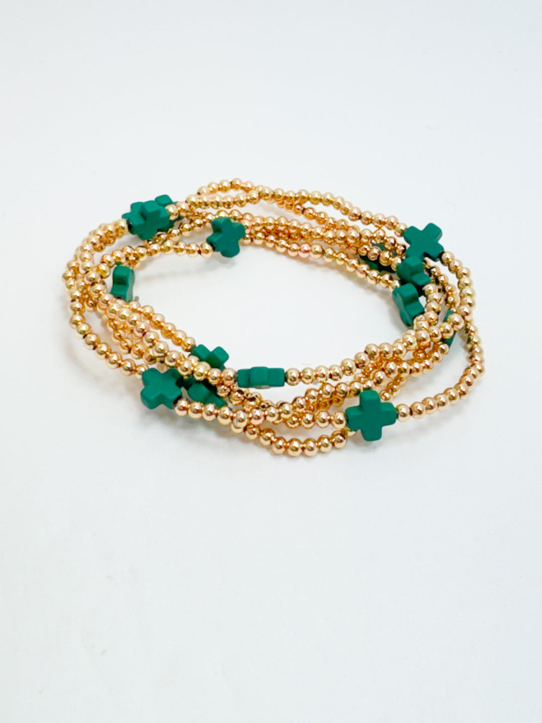 Gold bracelet with green clover-shaped beads on a white background