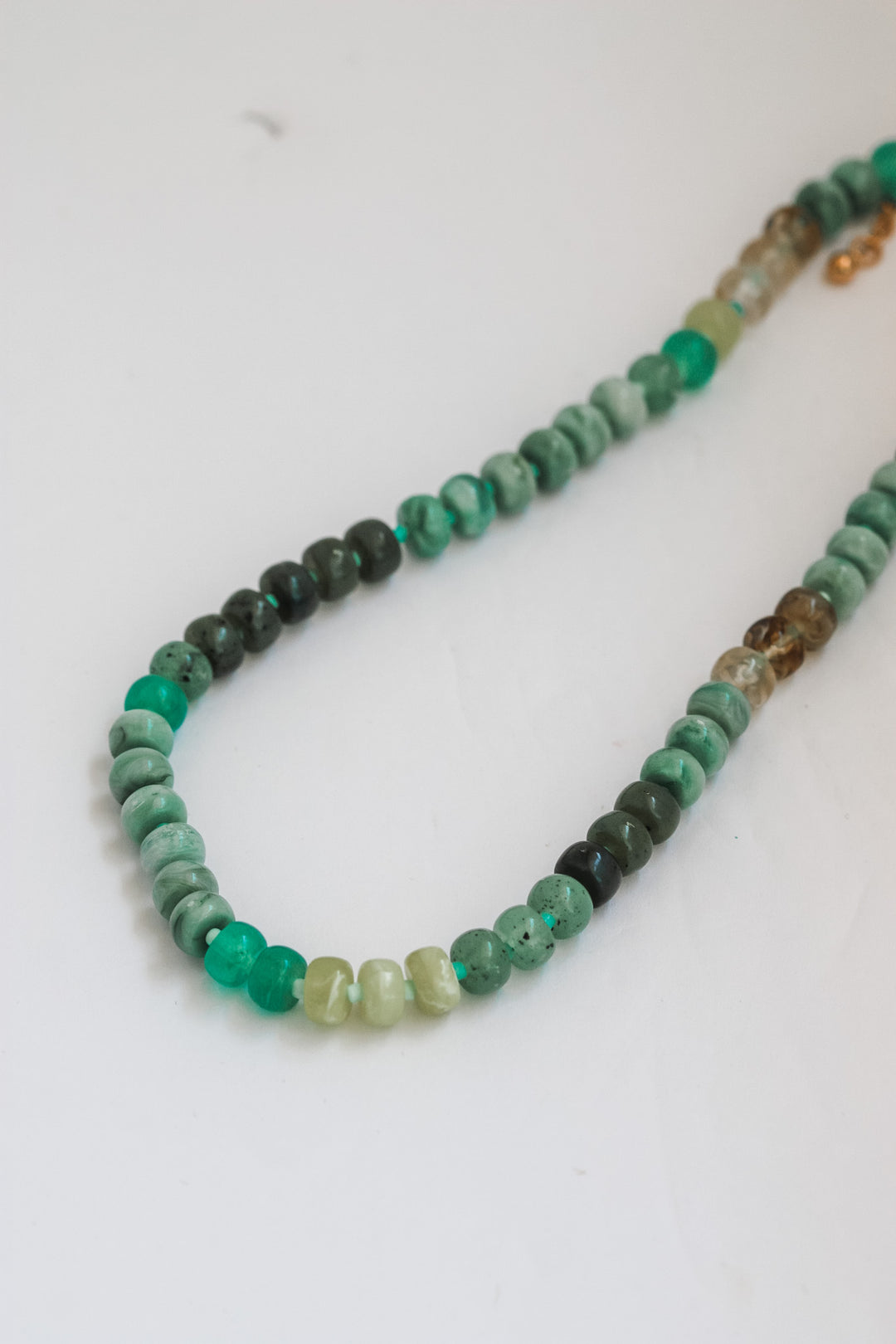 Necklace with green and brown beaded strands on a white background