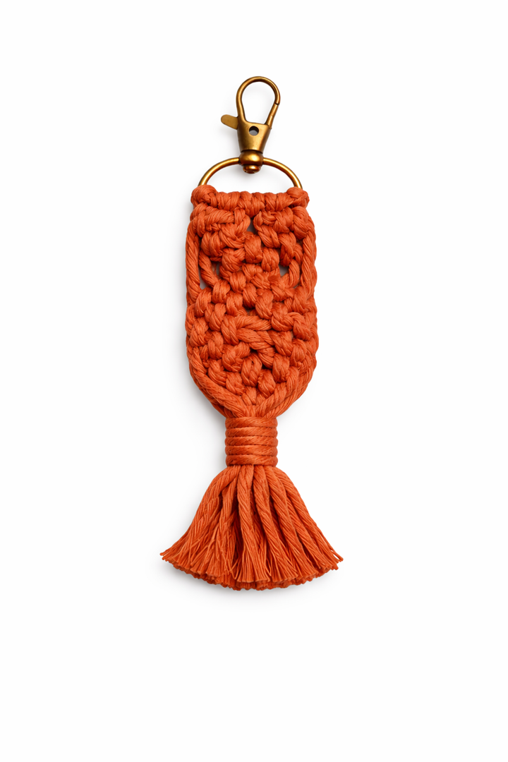 Orange macrame keychain with a gold clasp on a white background
